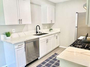 A kitchen with white cabinets and a stainless steel refrigerator